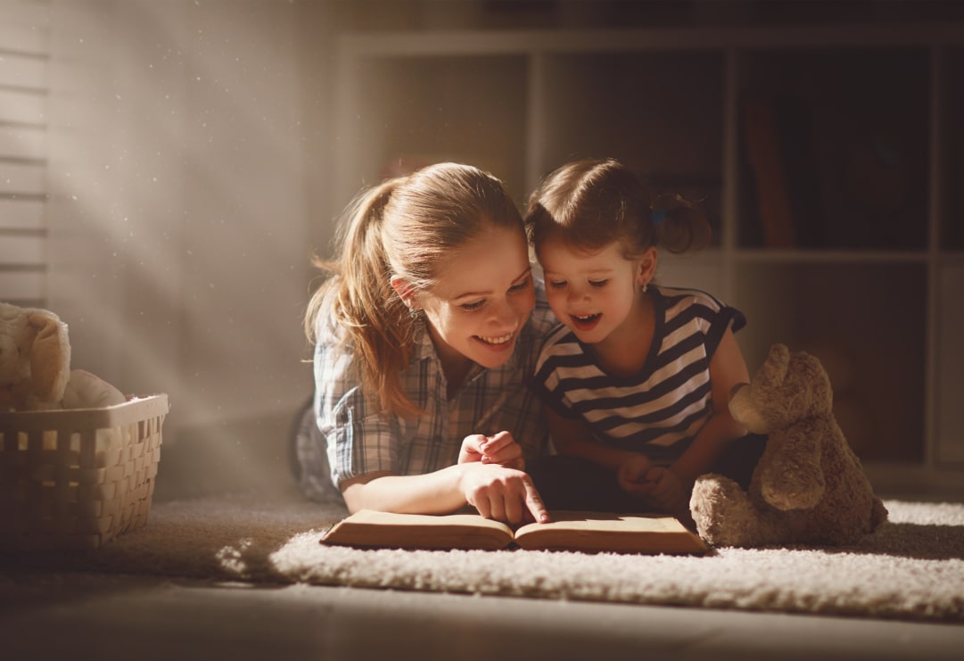A smiling mother reading to her daughter in warm sunlight, symbolizing Latattore Foundation’s focus on early literacy and nurturing family bonds